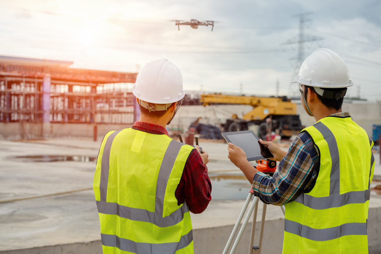 Two construction workers operating drone on building site