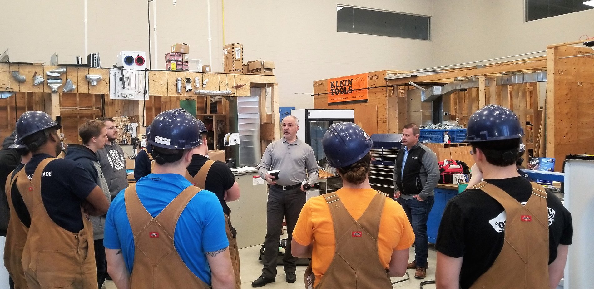 An instructor talking to a group of trades students in the Herzing workshop
