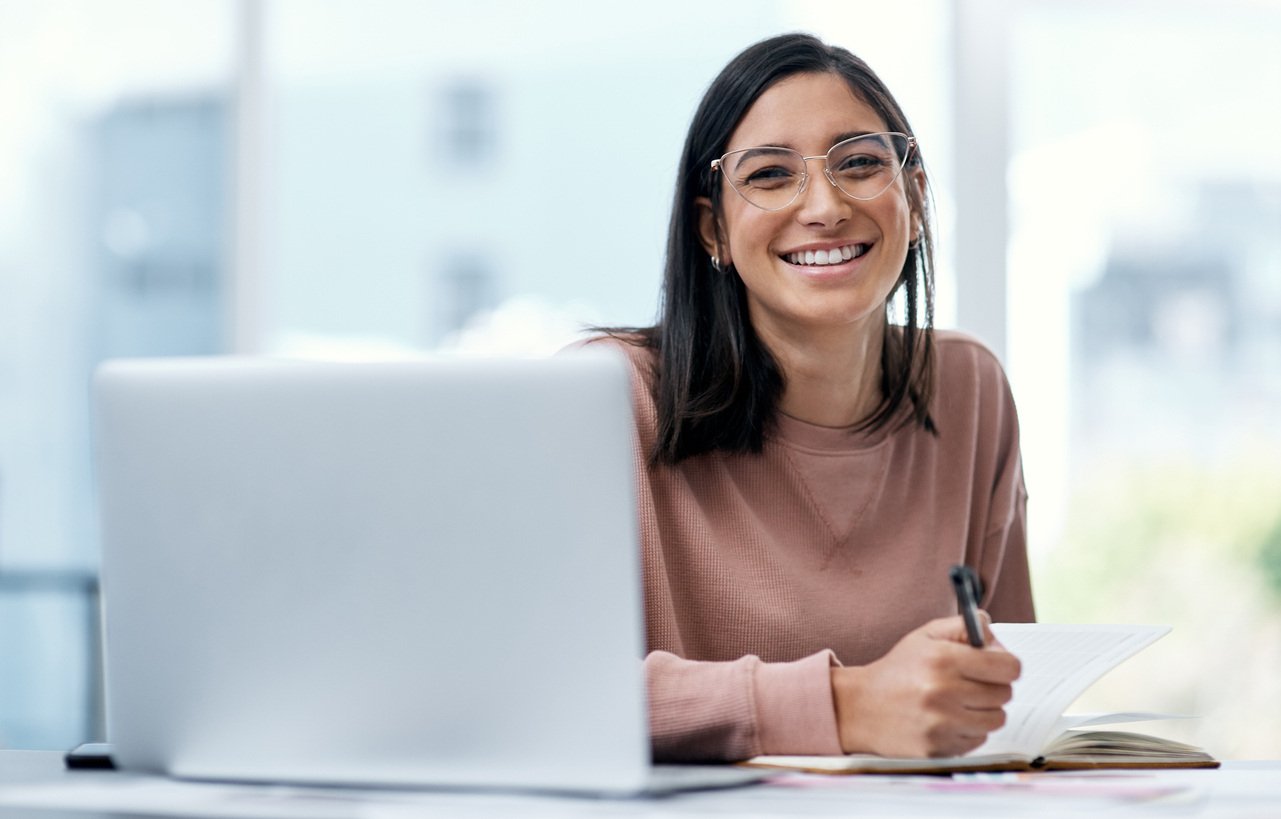 Smiling young woman using a laptop while working from home