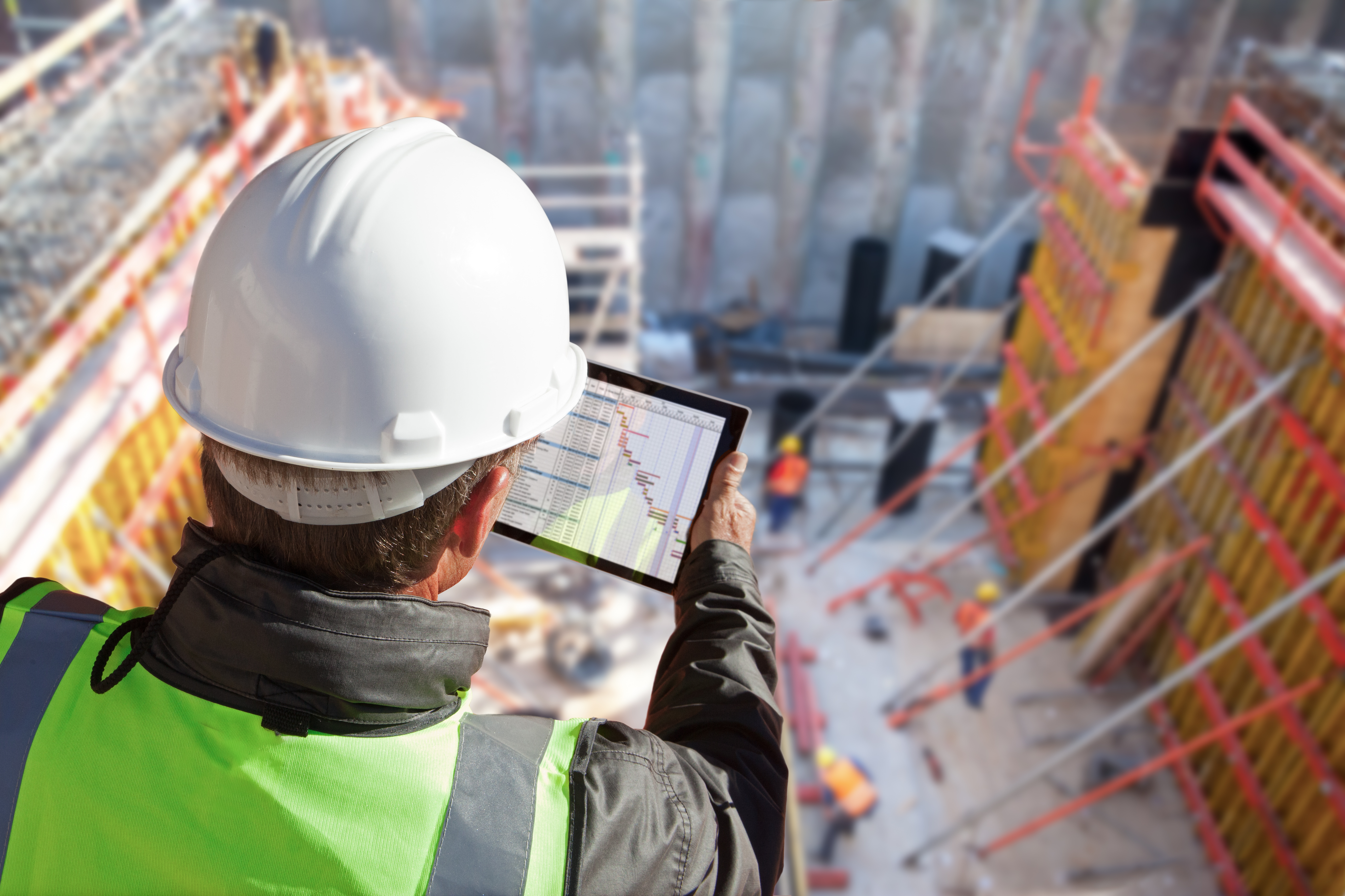 Construction manager with tablet overlooking building site