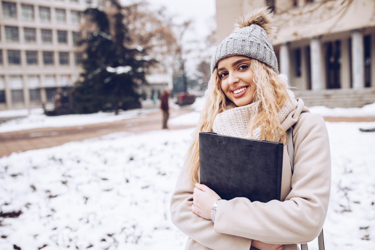 Smiling student wearing winter gear and standing outside in snow